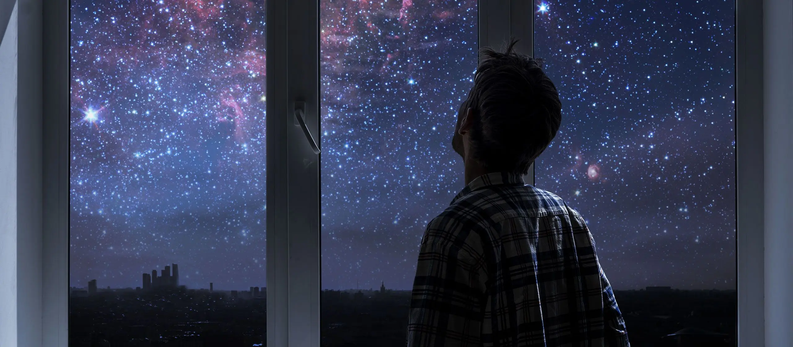 Mann som ser ut av vinduet på stjernehimmelen